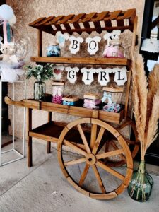 Candy bar installé pour une gender reveal avec décorations et friandises sur un chariot en bois.