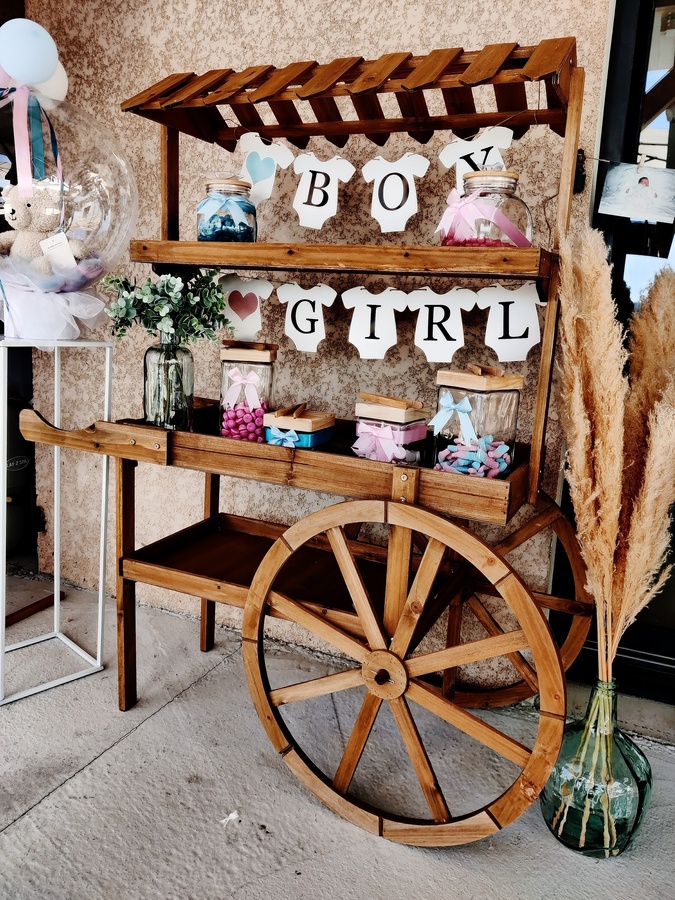 Candy bar installé pour une gender reveal avec décorations et friandises sur un chariot en bois.