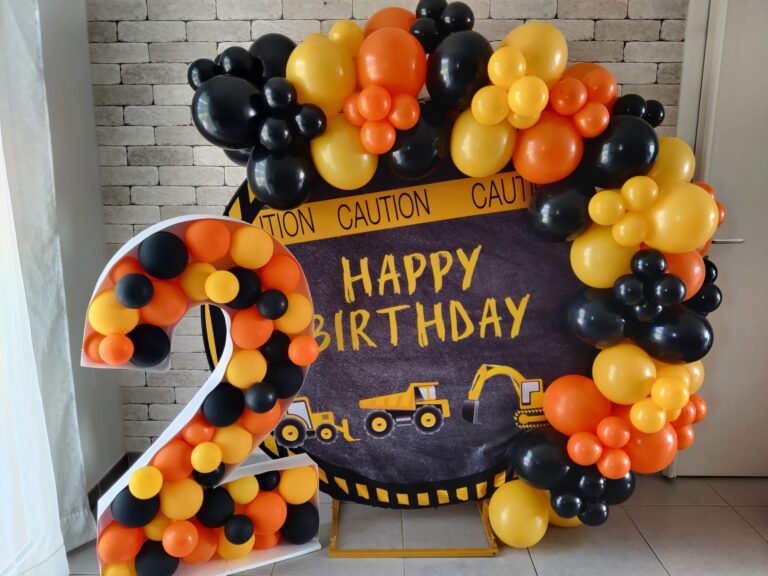 Décoration d'anniversaire thème camions avec ballons orange, noir et jaune par CinDéco.