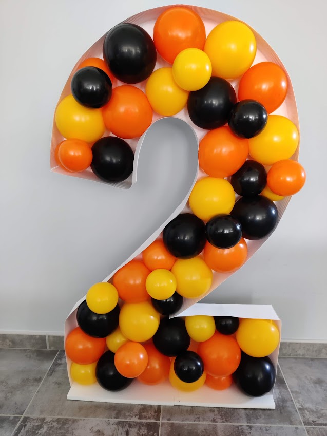 Chiffre 2 décoré avec des ballons orange, jaune et noir, utilisé pour une décoration d'anniversaire.